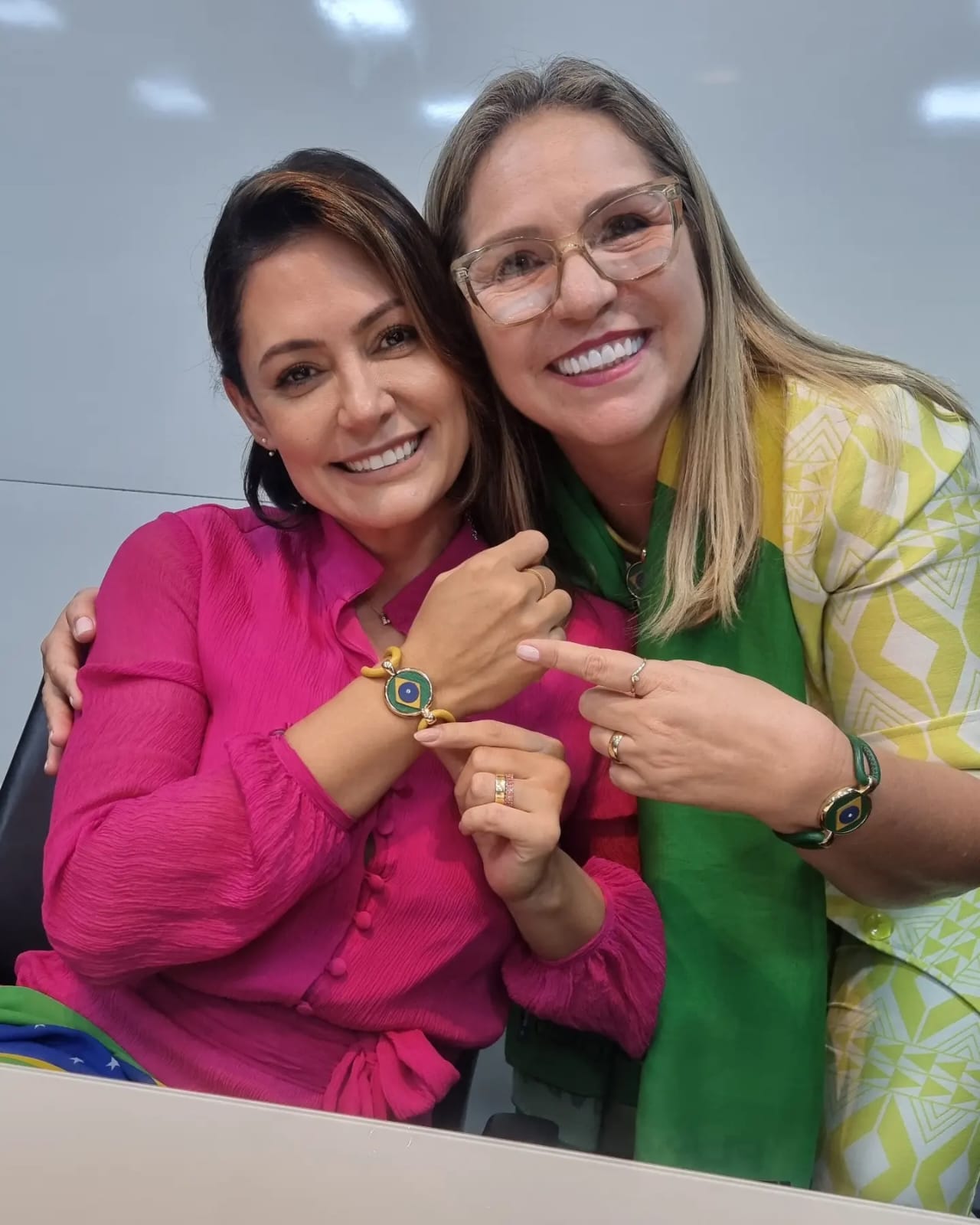 Flávia Berthier e Michelle Bolsonaro sorrindo com a pulseira do Brasil